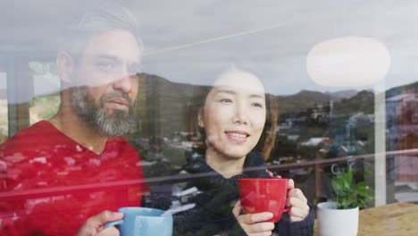 happy diverse couple drinking coffee and talking together at home