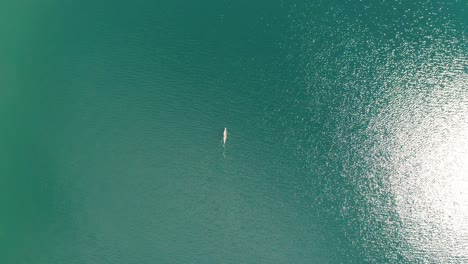 Aerial-top-down,-kayaker-paddling-on-a-vast-turquoise-lake