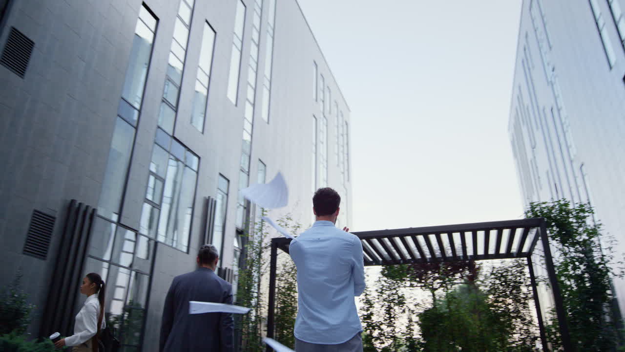 분노한 매니저가 사무실 건물 밖으로 종이를 던지는 감정적 붕괴.