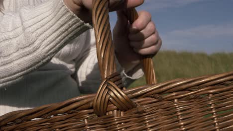 mujer sosteniendo una canasta tejida en el campo primer plano