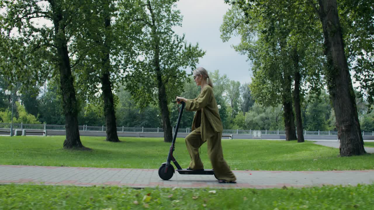 Mujer montando en un patinete eléctrico en un parque
