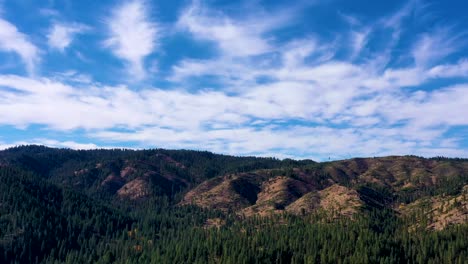 Drone-Aerial-push-in-time-lapse-over-mountain-range-covered-with-forest-trees