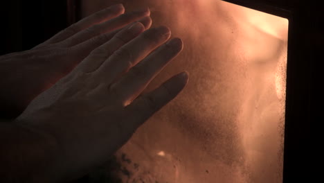 hombre frotándose las manos frías junto a la chimenea calentándose