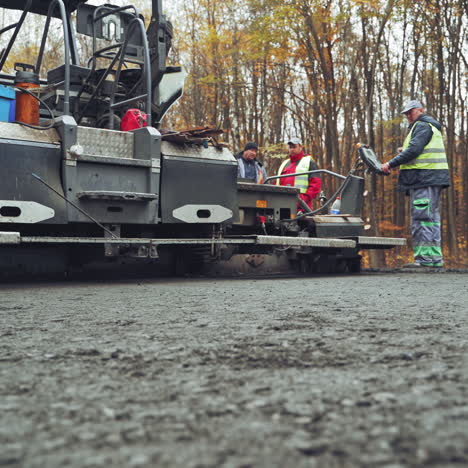roadworks repaving process. workers applying new hot asphalt using road construction machinery and power industrial tools. camera moves forward.
