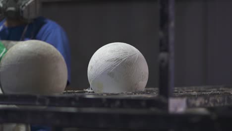 Balones-De-Mano-Formados-En-Tela-Esperan-En-La-Estación-De-Trabajo-Mientras-El-Trabajador-De-La-Fábrica-Pega-Sus-Fundas