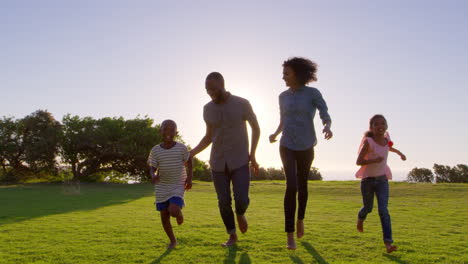 young black family running towards moving camera in a park