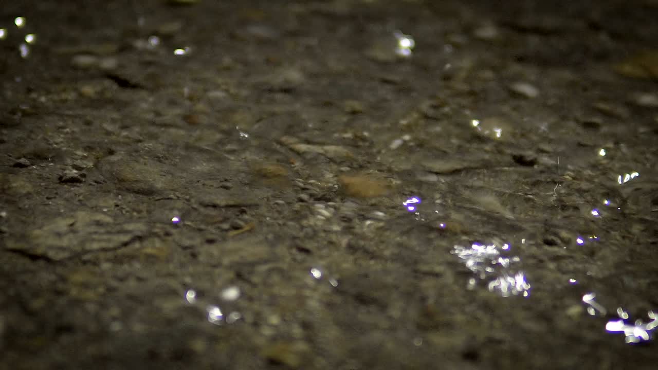 Rain drops on the asphalt floor at night time, Loopable background