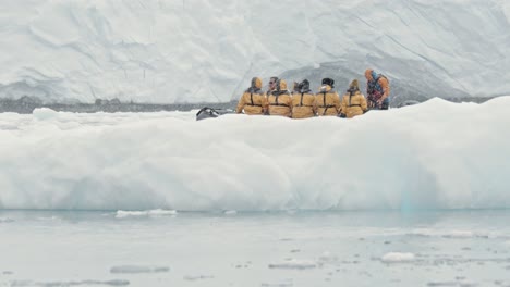 barco con turistas conduciendo alrededor de un iceberg en la antártida
