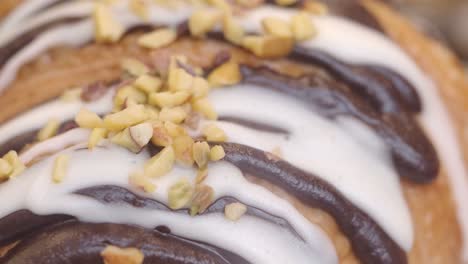 close-up of a chocolate and icing croissant with pistachios