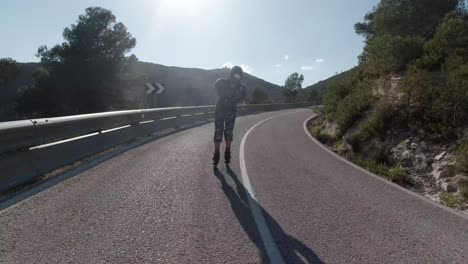 front facing follow shot of roller skater going downhill on mountain road