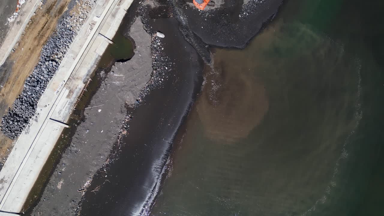 Aerial top-down view of idyllic shoreline by a construction area and excavator at Malilipot Seawall, Albay.