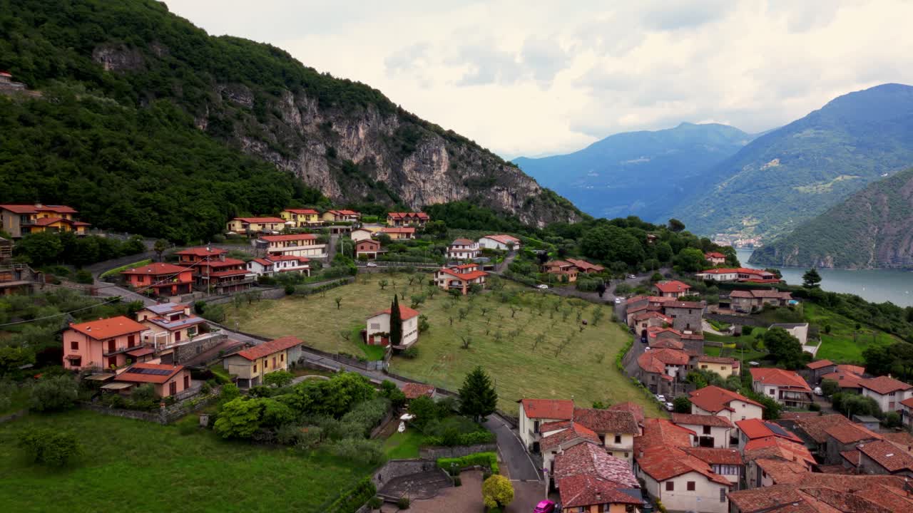 Aerial angle over traditional homes and small orchard at the foot of a steep, rocky hillside near Lake Iseo. Riva di Solto, Italy Riva di Solto, Italia