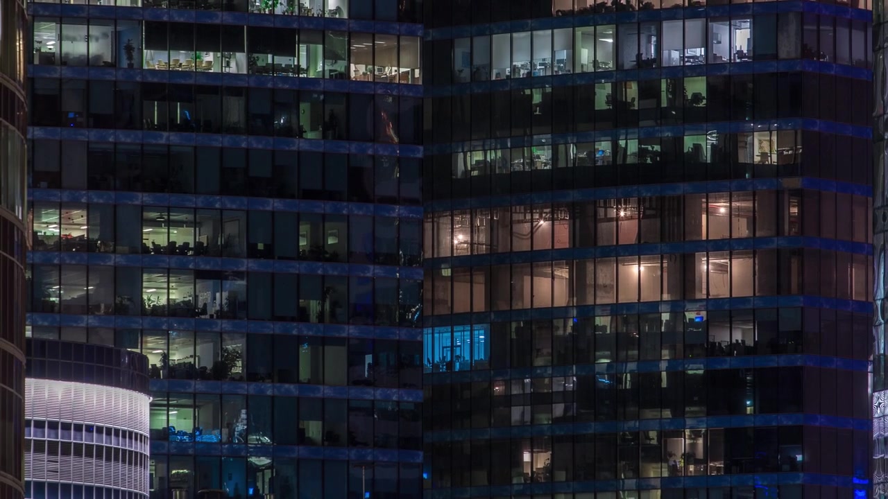 Vista ravvicinata delle finestre illuminate degli uffici nei grattacieli del Centro Affari Internazionale della Città di notte, timelapse dall'alto.