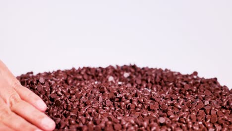 hands gently sort chocolate drops on a white surface, creating a calming and tactile visual experience