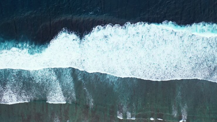 Sea waves texture seen from above showing energy of ocean by big waves splashing on shallow lagoon with rocks and coral reefs in Australia