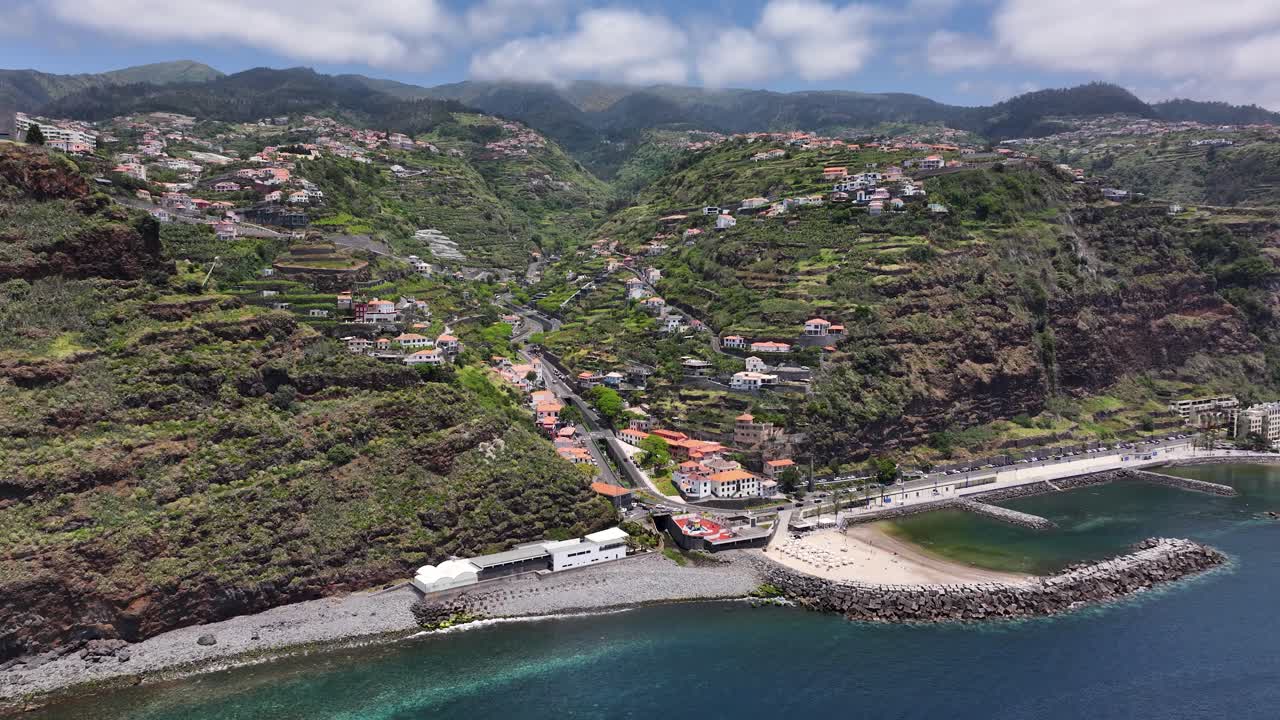 Scenic Calheta seaside resort on Madeira coastline, drone pullback riser reveal