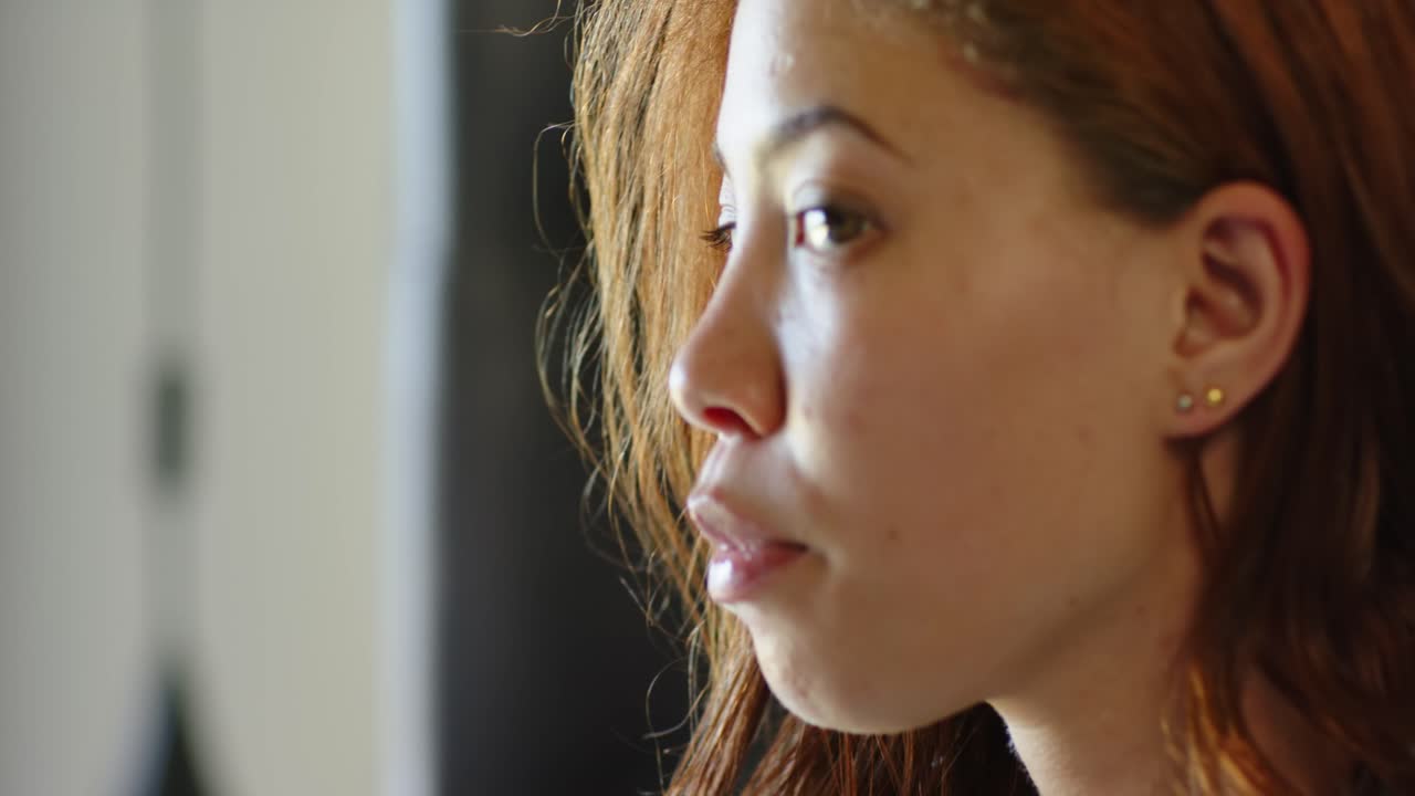 African American woman mid20s responding to off-frame voice, speaking, brushing hair facing camera