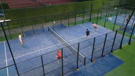 Aerial view of a padel game in progress, showing player interaction, court layout, and energetic movement