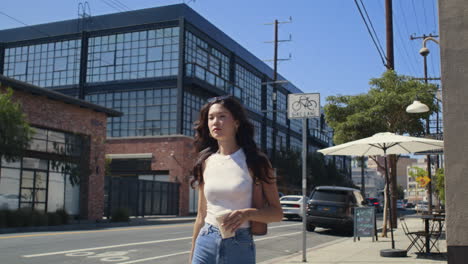 la chica disfruta del café caminando por la calle de cerca. la mujer asiática sostiene la taza y cruza el cruce de peatones.