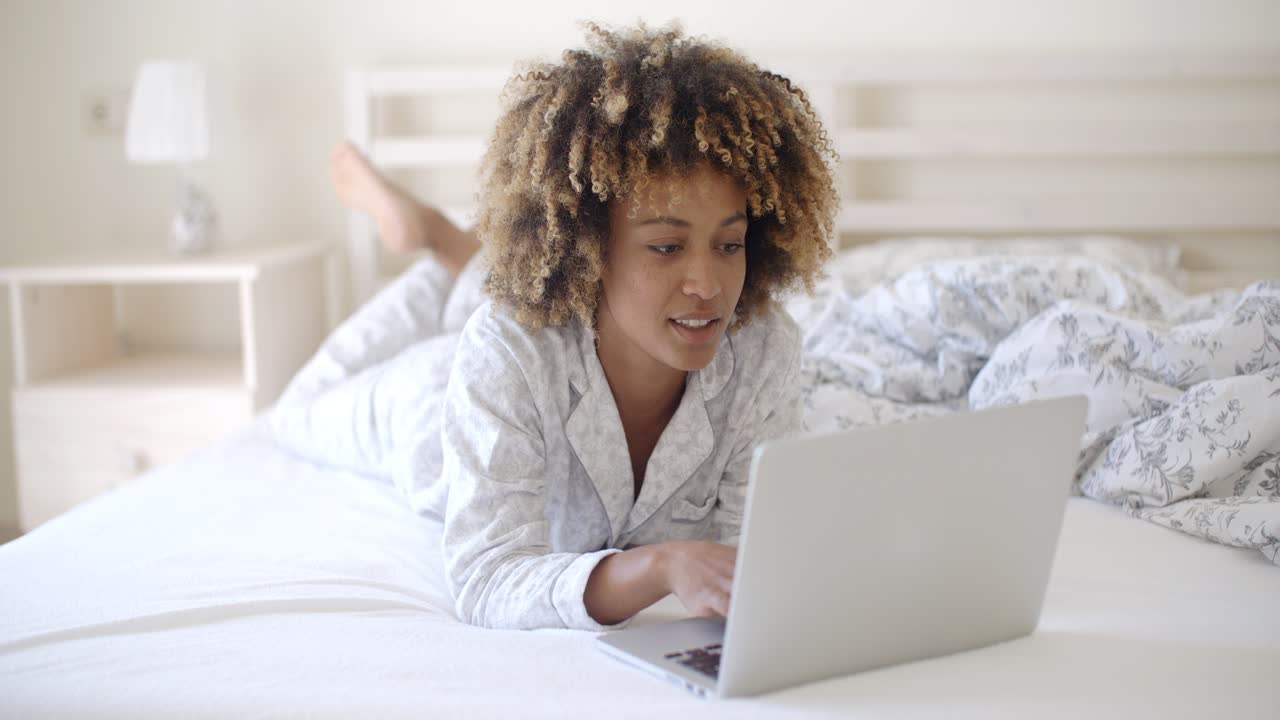 Woman Looking At Laptop In Bed At Home