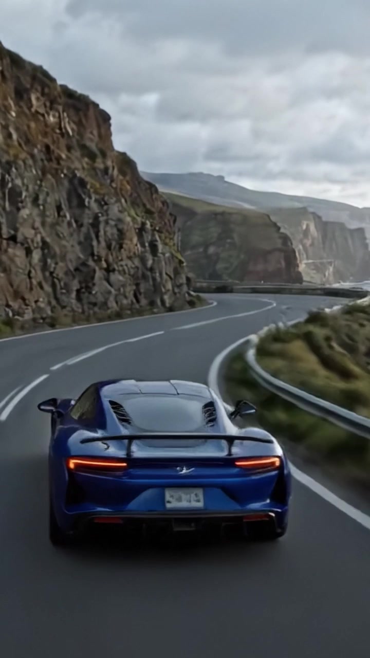 Un viaggio mozzafiato lungo la strada costiera: catturando la maestosità di scogliere, onde e un'elegante auto sportiva blu in un paesaggio pittoresco.
