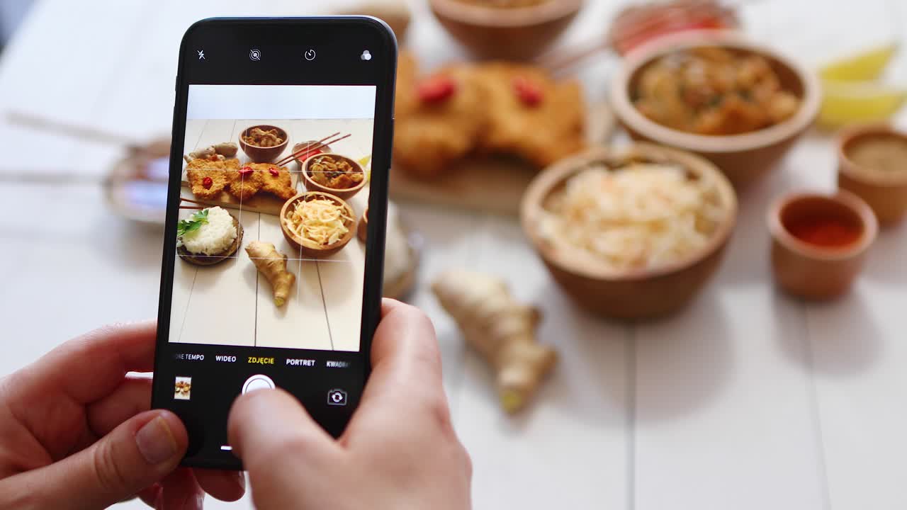 mujer tomando una foto con un smartphone de pollo crujiente frito en pan rallado