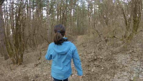 girl walking in between trees on a mountain trail, during autumn