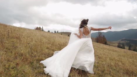 Bride-woman-newlywed-in-wedding-stylish-dress-walking-or-running-on-mountain-slope-hill-to-groom