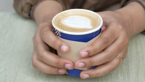 quita la taza de café de papel de la mesa de la cafetería .