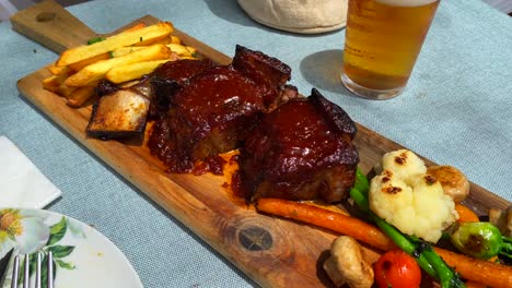 tender slow cooked beef ribs in bbq sauce with french fries and vegetables, tasty food in a restaurant, 4k shot