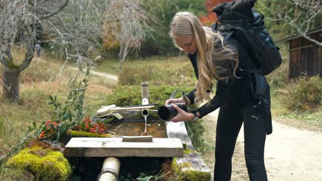 A serene stock video of a girl filming by a tranquil fountain along the Nakasendo Trail in Japan.