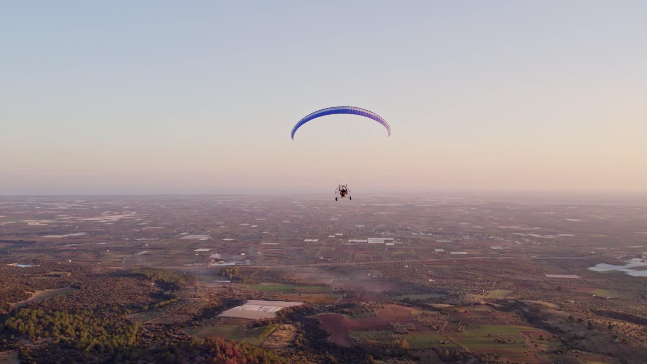 Paramotor gün batımında Ginosa üzerinde süzülüyor, canlı şehir manzarası, Taranto, İtalya