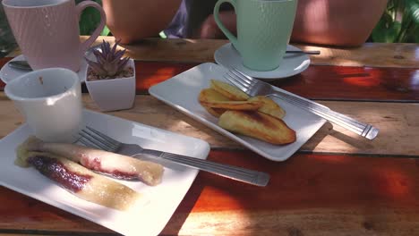 vista aérea de una merienda filipina tradicional de suman y kamote frito servido con café con vista parcial de una persona comiendo