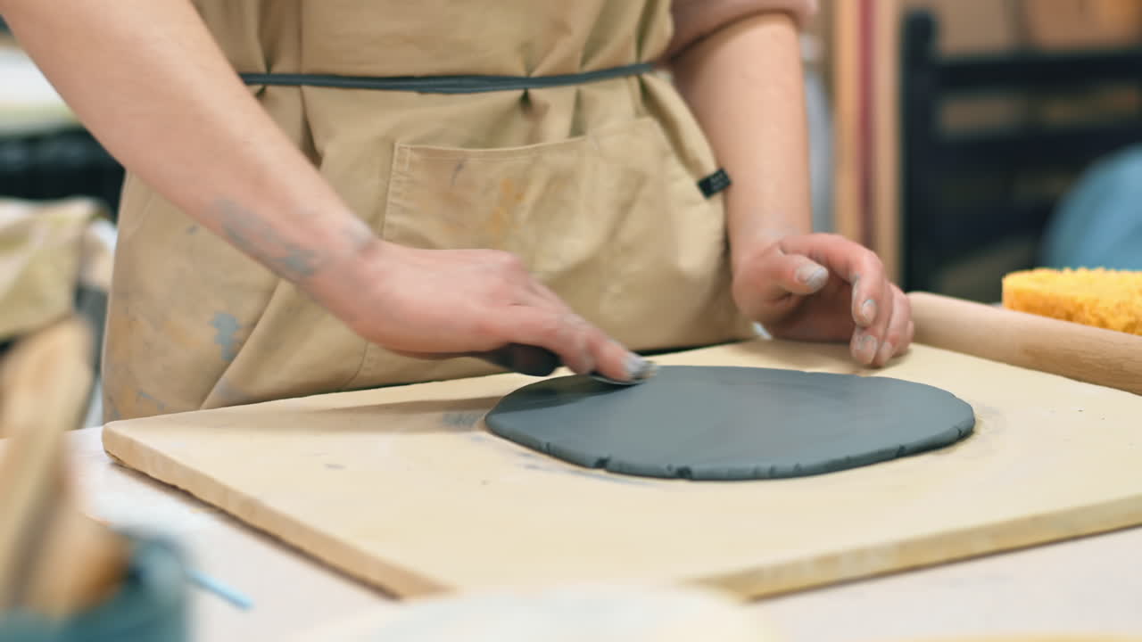 The master of sculpting pottery working in a studio. Smoothing clay. Tools and materials on the table