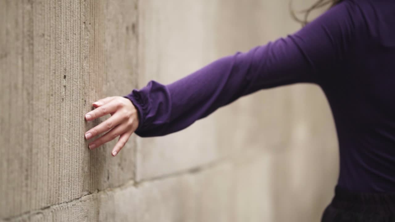 바람이 많이 부는 날씨 slowmotion에서 벽을 만지고 걷는 여성 손 클로즈업