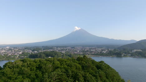 aerial tracking shot of a island on lake kawaguchi with mt fuji in the background