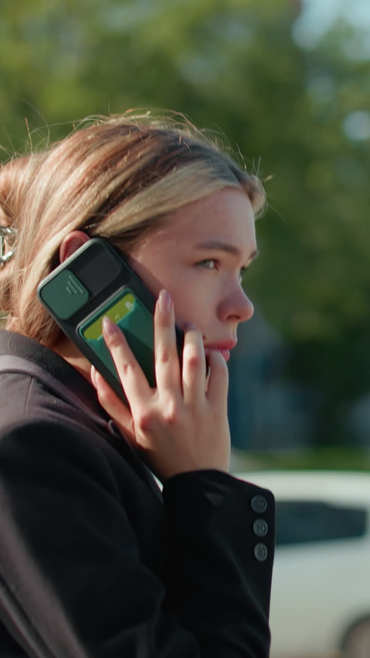 Lady resumes phone call after taking deep breath, standing in busy urban setting with blurred background of cars and pedestrians, dressed in professional attire