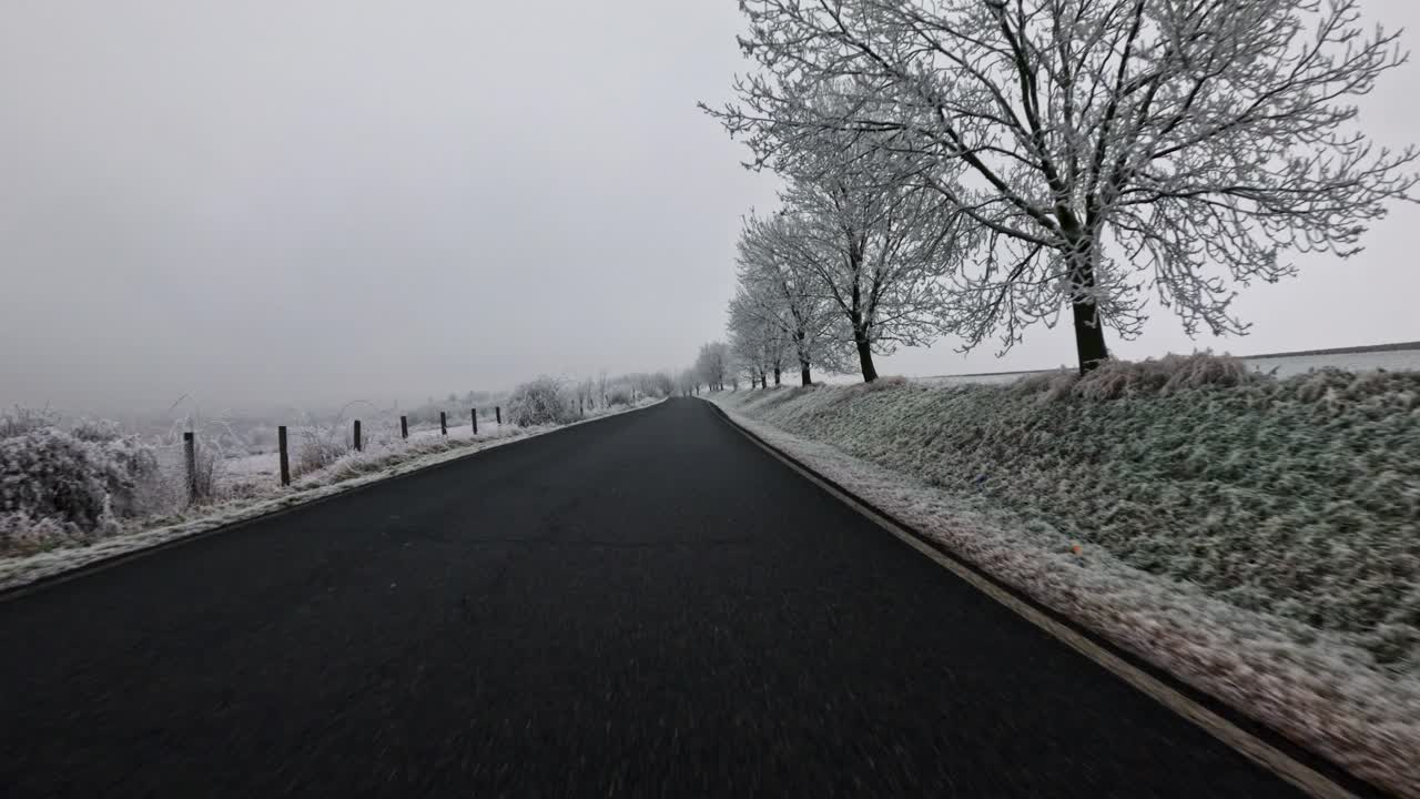 POV from a car riding on an open road in snowy winter, overcast