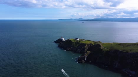 aerial orbiting shot of a lighthouse at the end of a rocky peninsula in ireland