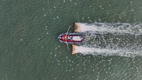 Drohnenaufnahme-Von-Oben-Eines-Fischerboots,-Das-Die-Netze-Durch-Das-Wasser-Zieht