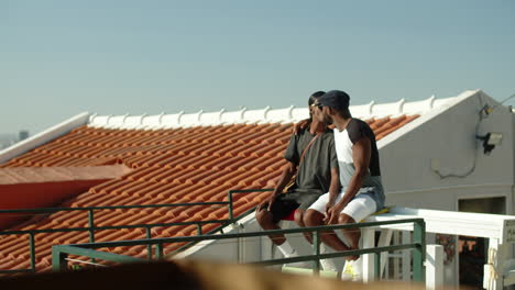 Long-shot-of-gay-couple-sitting-on-rooftop-and-kissing