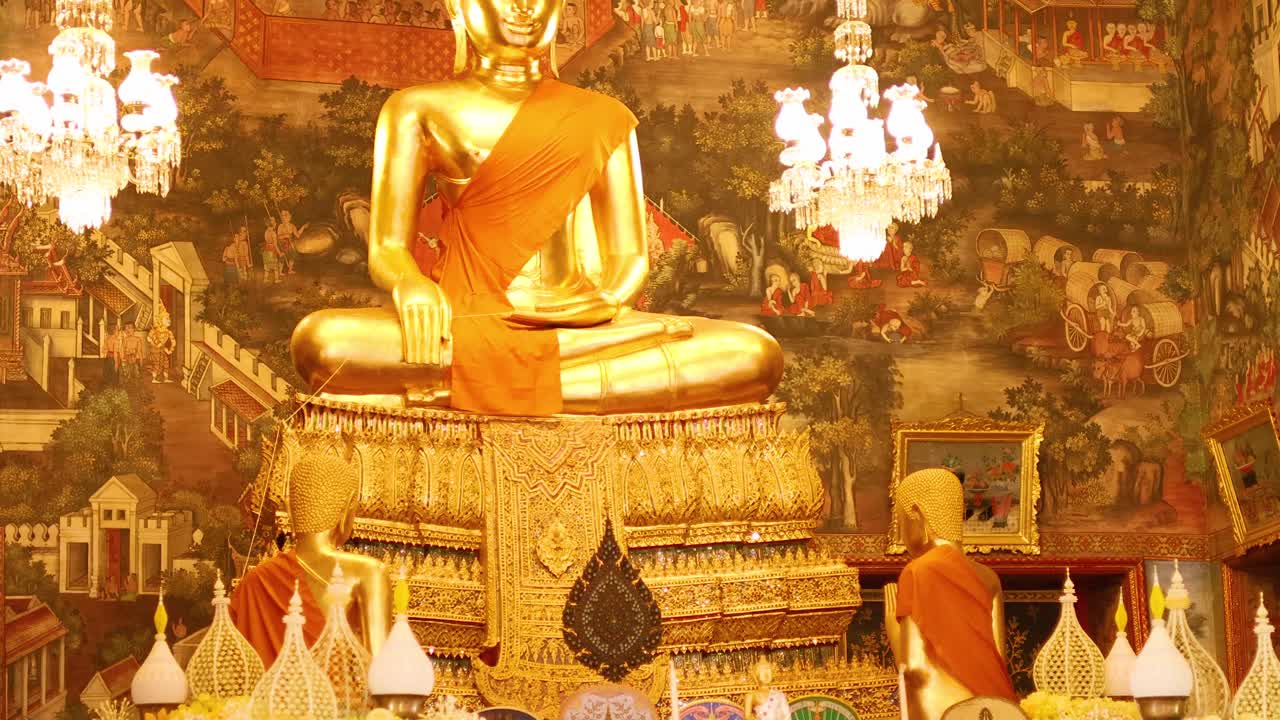 A serene golden Buddha statue surrounded by ornate decorations and vibrant flowers in Wat Arun, Bangkok, under warm lighting