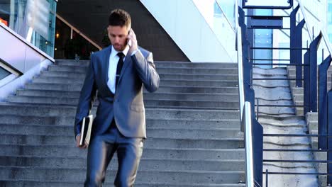 Businessman-with-a-diary-talking-on-mobile-phone-in-the-campus