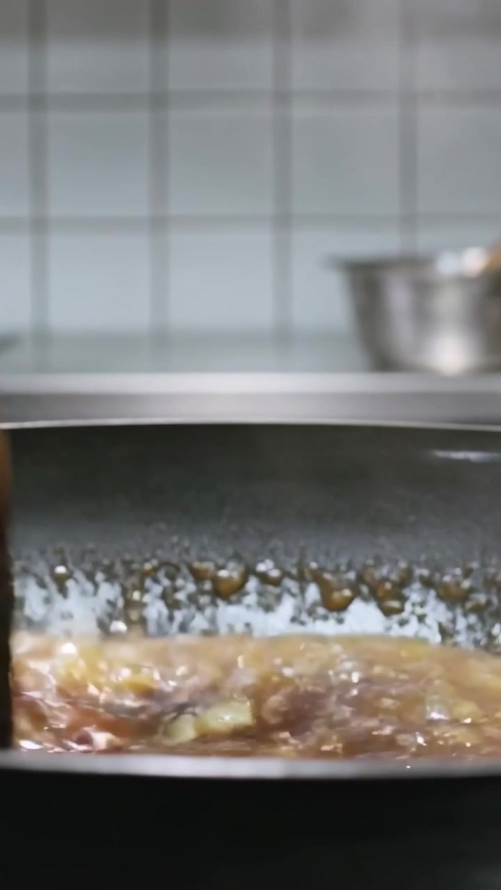 Vertical video: Bringing wooden spatula, cook's hand stirring sauce in pan on stove mixing to boil