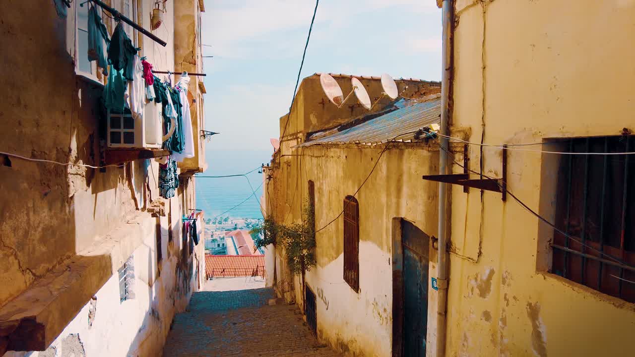 Un piccolo vicolo nel quartiere della Casbah di Algeri che si affaccia sul Mar Mediterraneo sullo sfondo