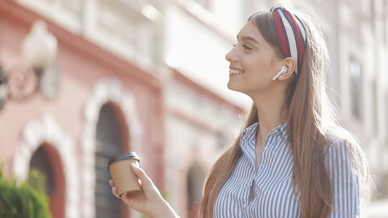 Giovane donna felice che beve caffè e ascolta musica all'aperto
