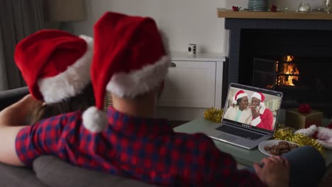 Kaukasisches-Paar-Bei-Einem-Videoanruf-Auf-Einem-Laptop-Mit-Einem-älteren-Paar-Zur-Weihnachtszeit