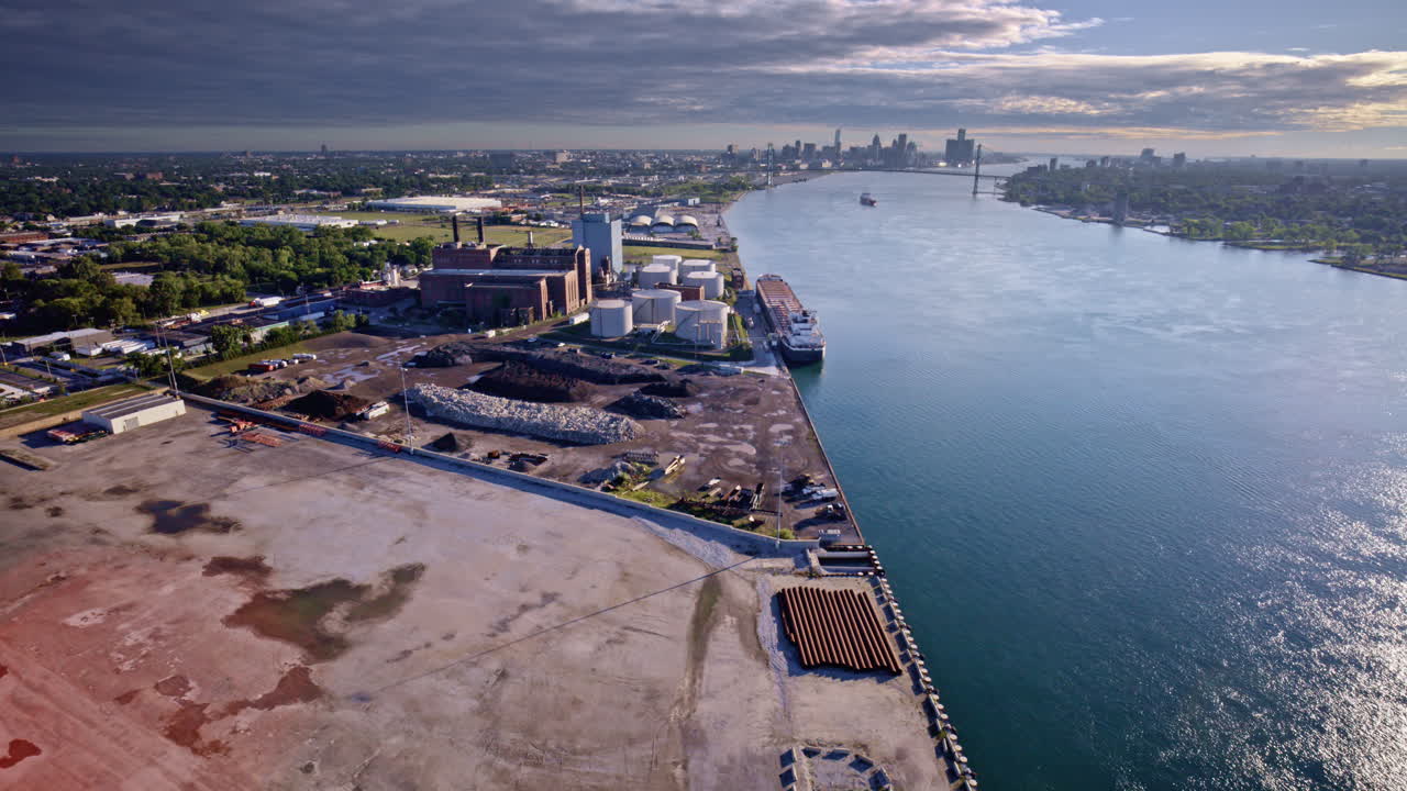 Sweeping cinematic drone pass over the Detroit River featuring a cargo ship beneath the skyline