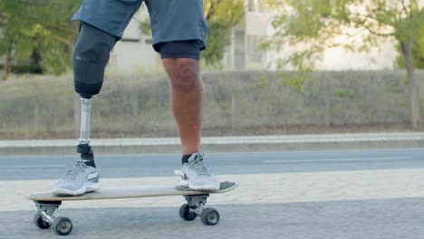 hombre con pierna protésica empujando lejos del suelo y patinando