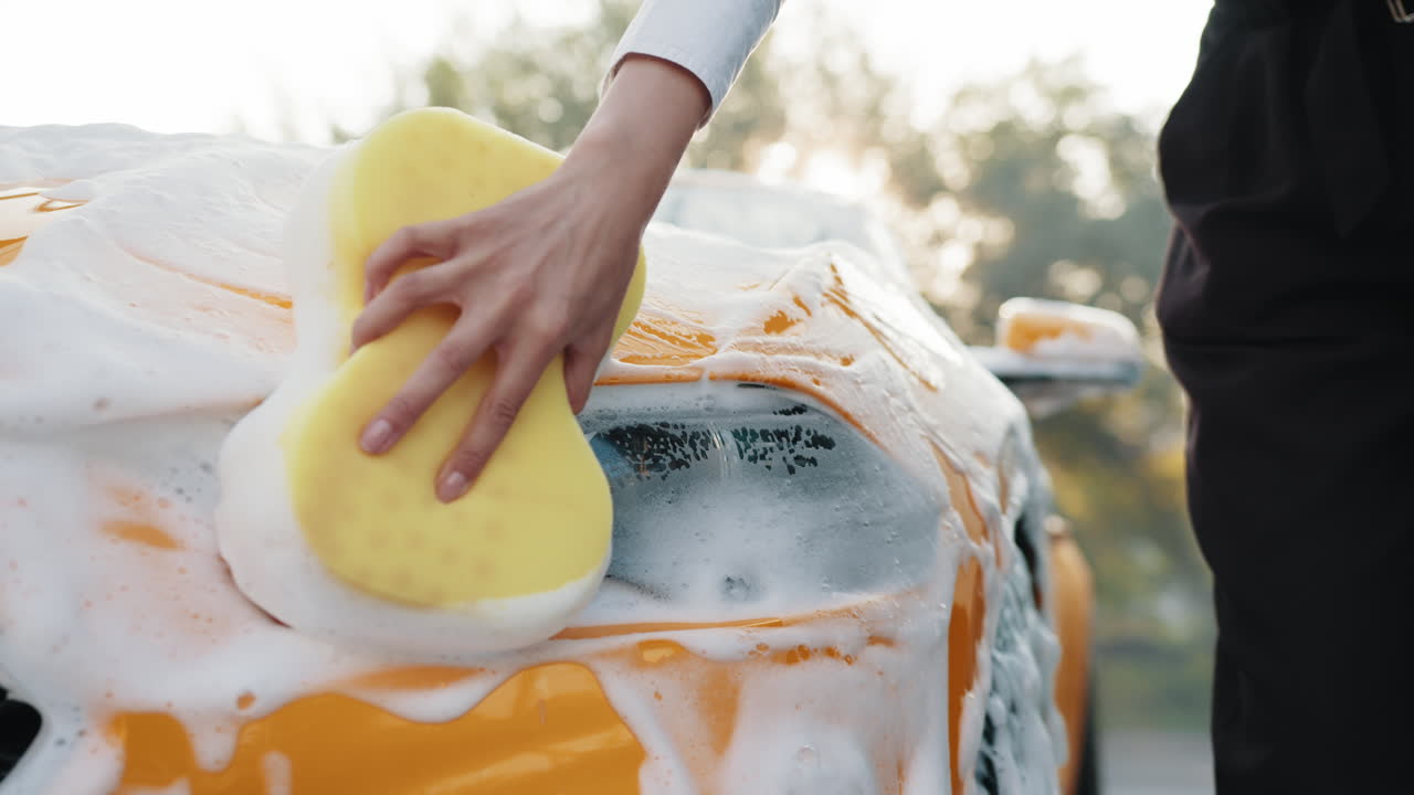 mujer lavando un coche amarillo con espuma